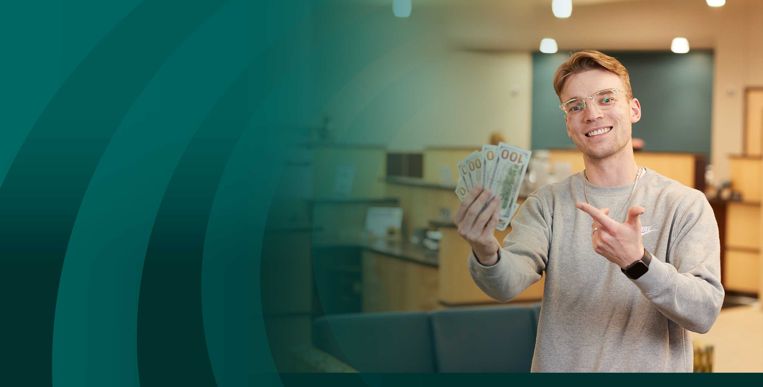 Man fanning out cash and pointing at a Community First Credit Union branch